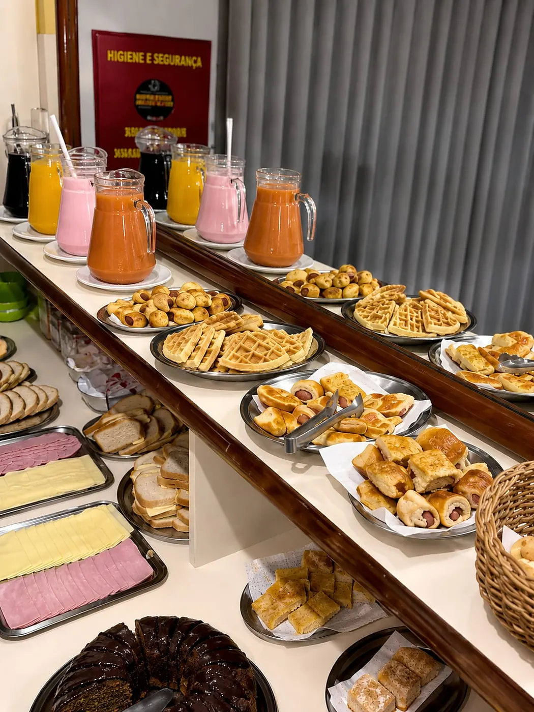 Buffet do café da manhã do Hotel Tubarão: jarras de sucos e vitaminas, waffles, pães, frios e bolo de chocolate