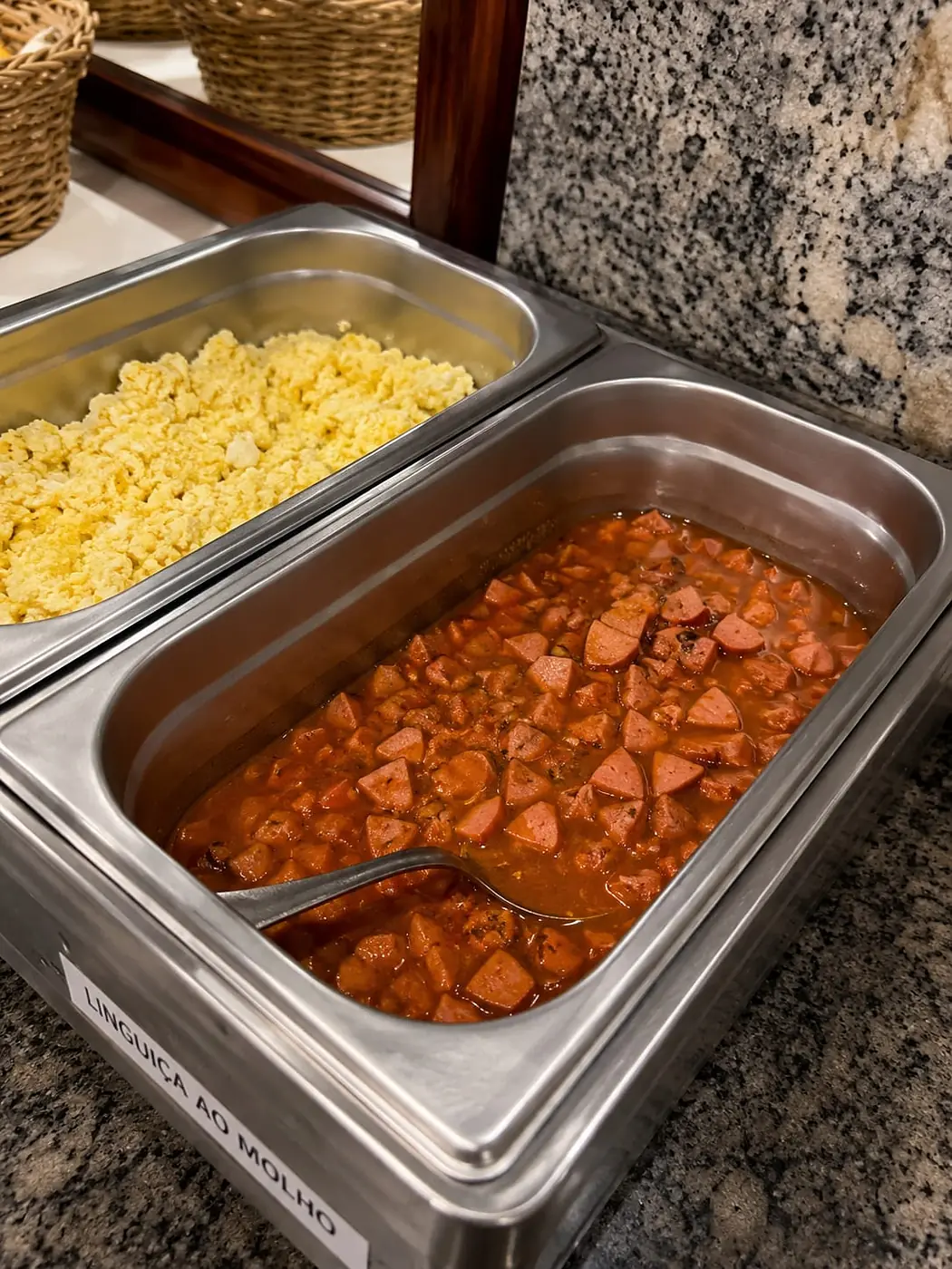 Opções quentes do café da manhã: ovos mexidos e linguiça ao molho em rechauds