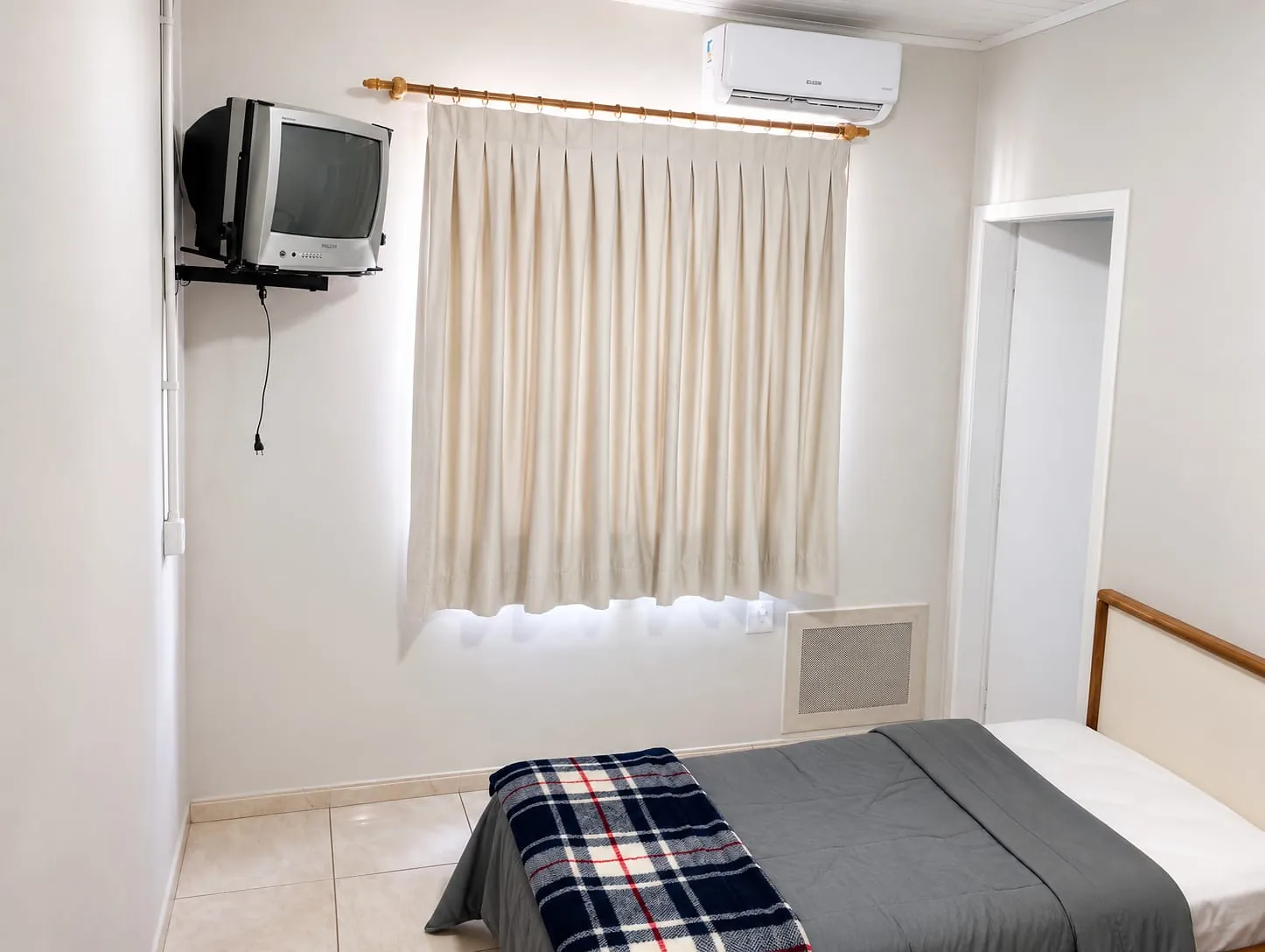 Quarto Econômico do Hotel Tubarão com cama de casal, TV e ar-condicionado