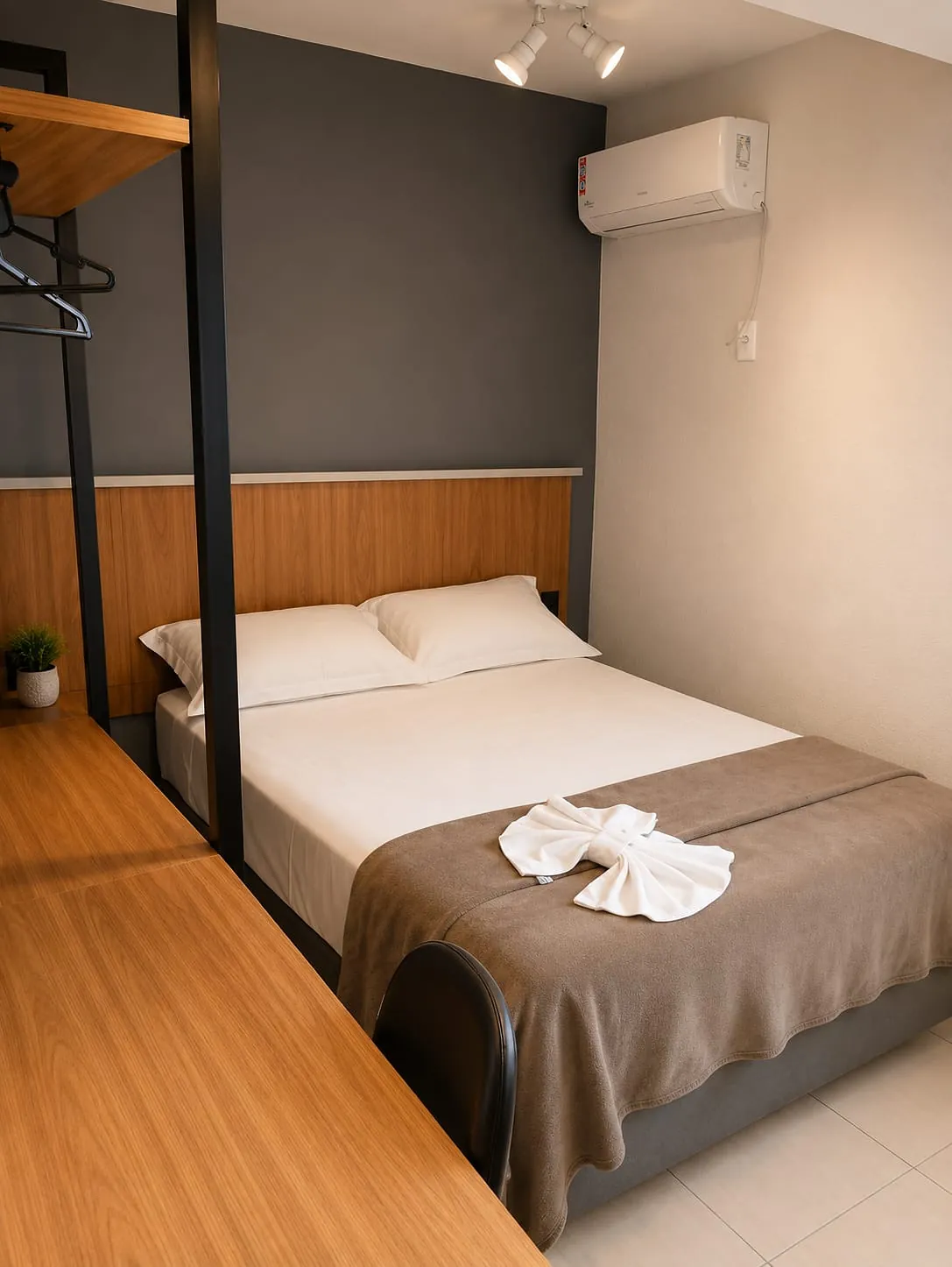 Cama de casal do Quarto Premium do Hotel Tubarão, com roupa de cama branca, manta e toalha decorativa