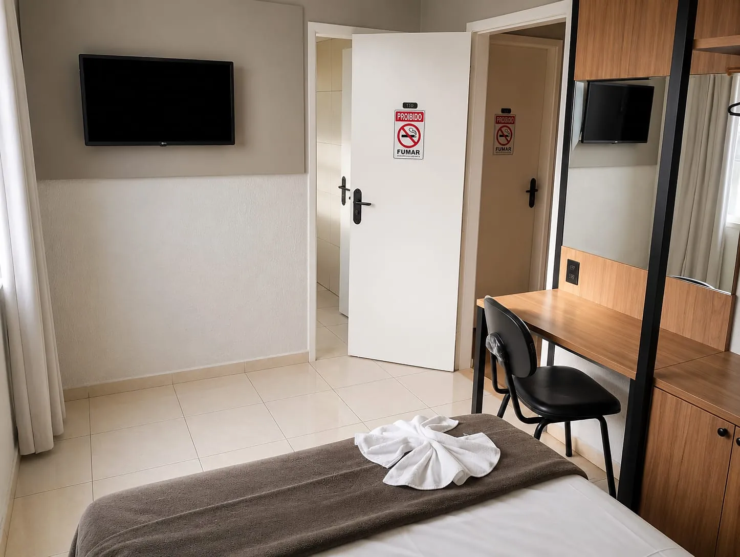 Entrada do Quarto Premium Casal do Hotel Tubarão, com TV, armário com espelho e acesso ao banheiro privativo