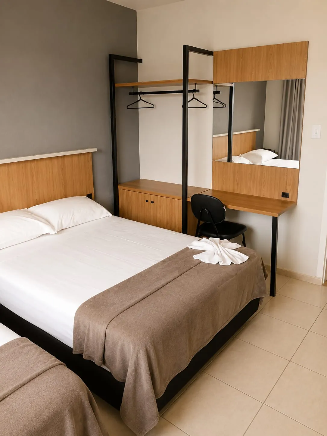 Cama de casal do Quarto Premium Família do Hotel Tubarão, com arara para roupas, escrivaninha e espelho