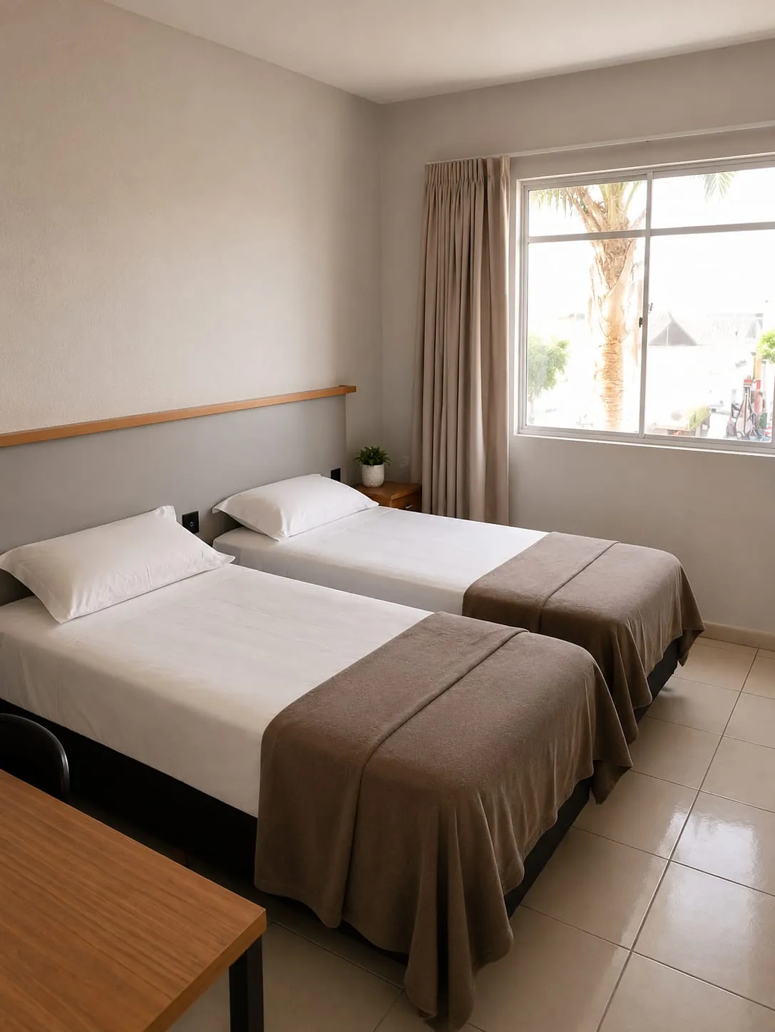 Camas do Quarto Premium Família junto à janela ampla com cortinas e vista para as palmeiras, no Hotel Tubarão